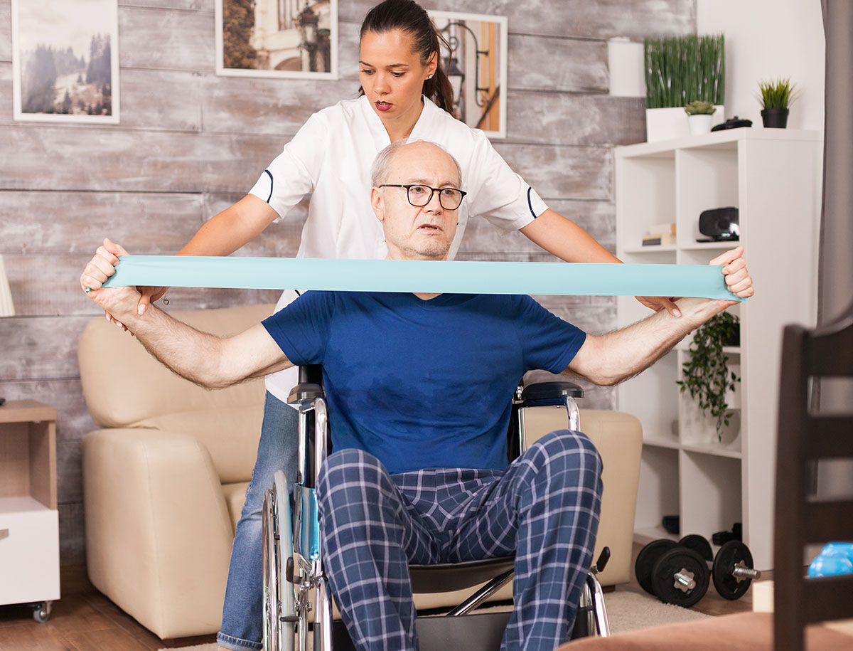 old-man-doing-muscle-injury-exercise-using-resistance-band-with-nurse-beside2